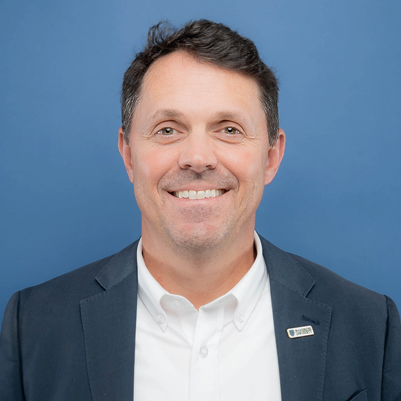 Don Courtright smiles into the camera against a blue background.