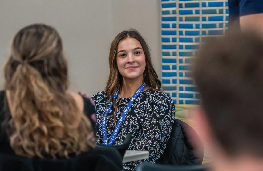 A student smiling while listening to someone speak