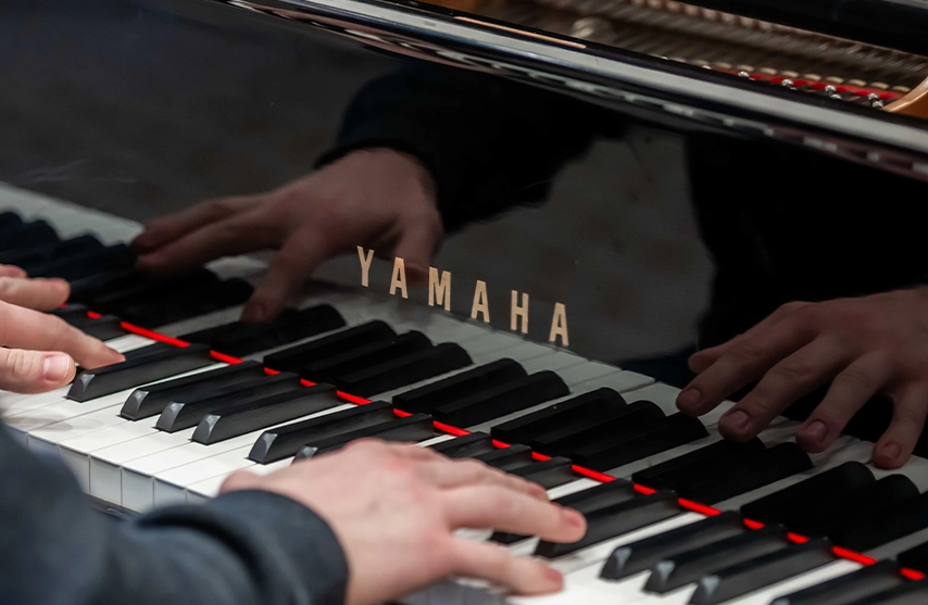 A close-up of hands playing the keys of a black piano.