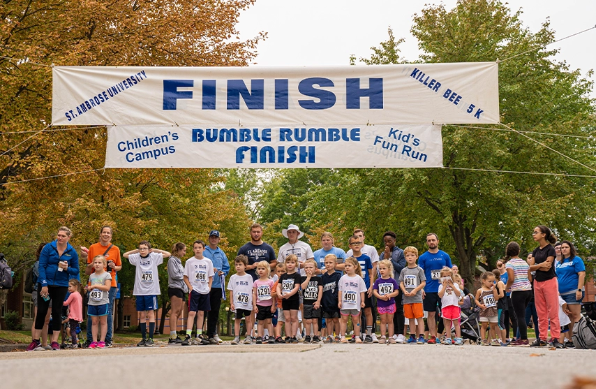 A group of children stand at the finish line of a race outside during the fall.