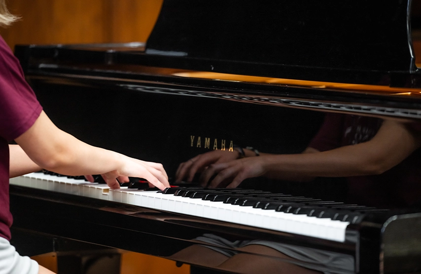 A close-up of a woman playing the keys of a black piano.