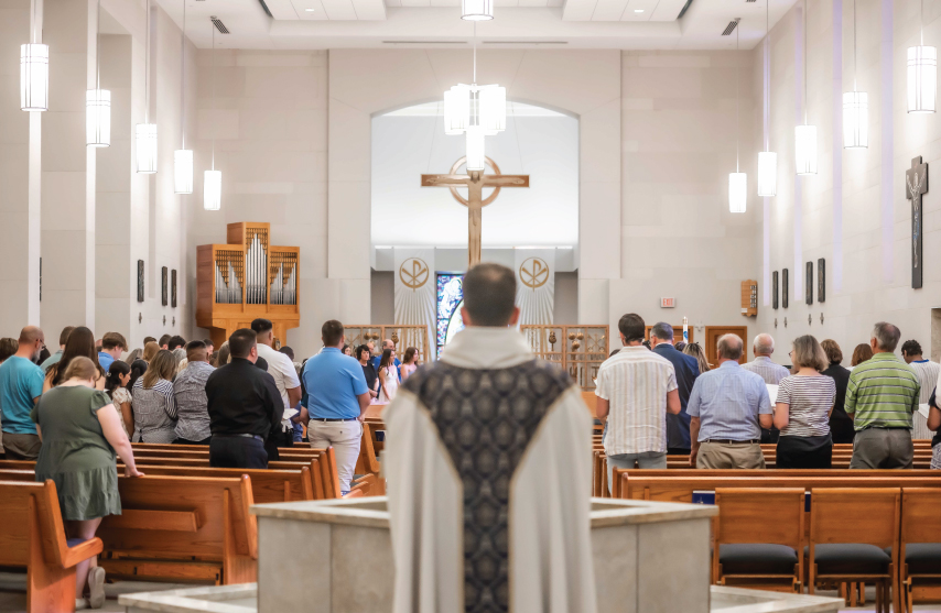 Priest standing at the back of a full mass