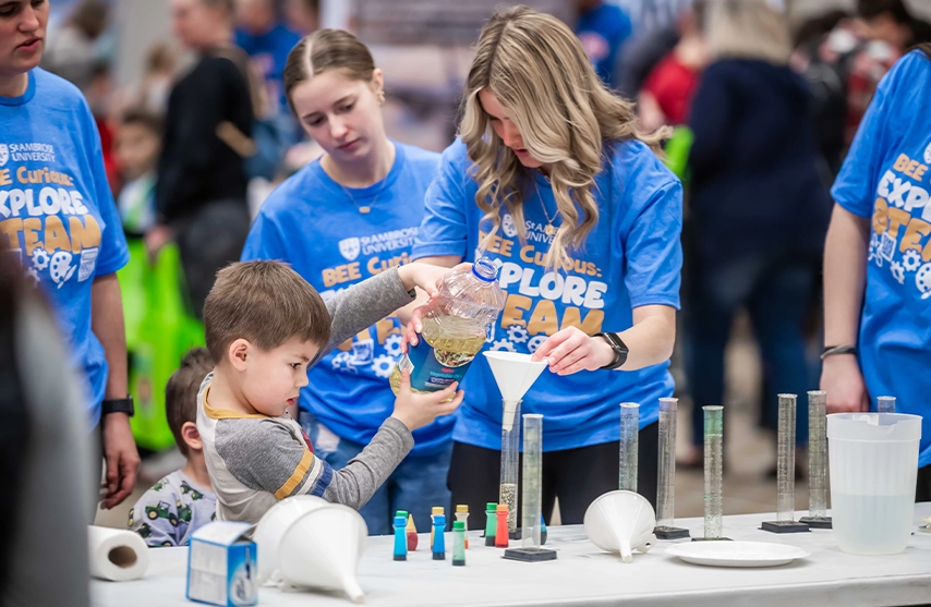 A woman helps a boy with a science experiment.