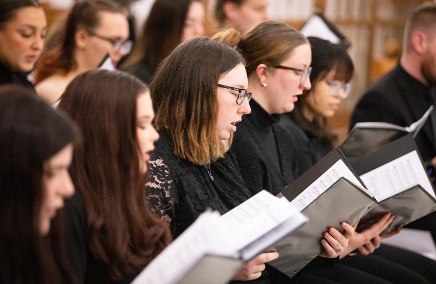 A choir dressed in black sings while reading music.