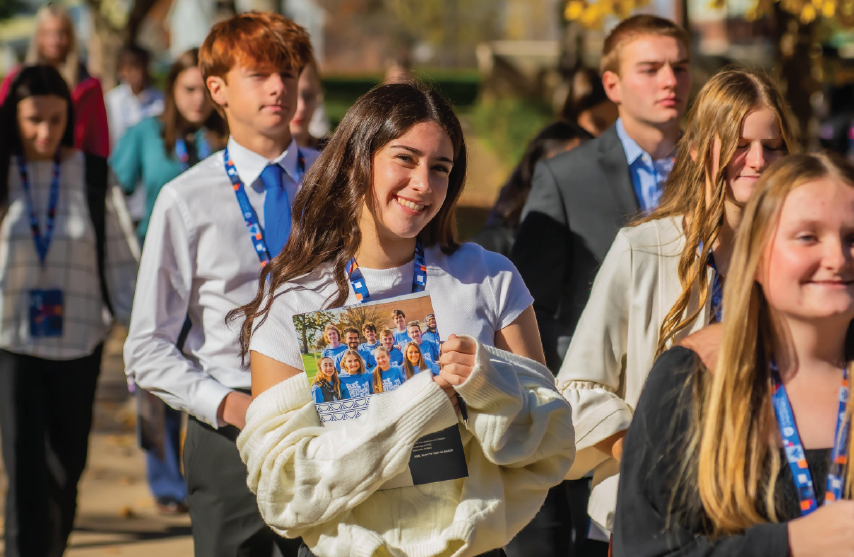 A student smiling at the camera while walking across campus