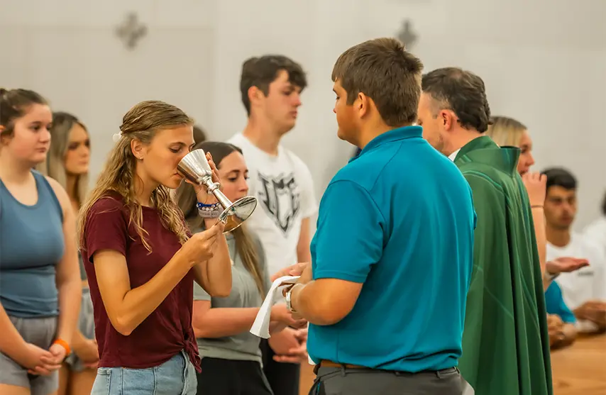 A woman drinks from a chalice during mass