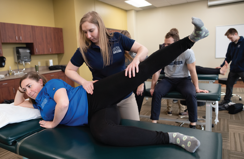 Physical therapist performing manual therapy in lab setting.