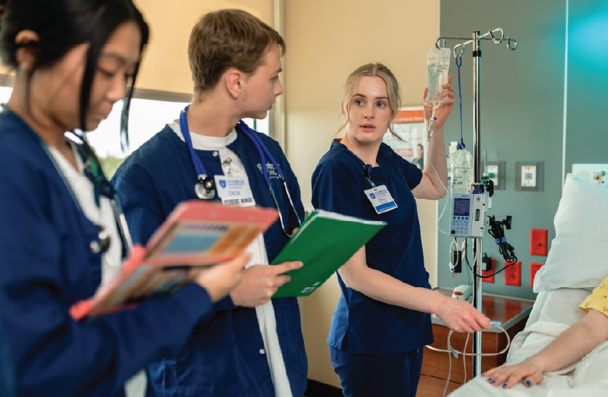 Three student nurses taking care of a patient in a lab setting