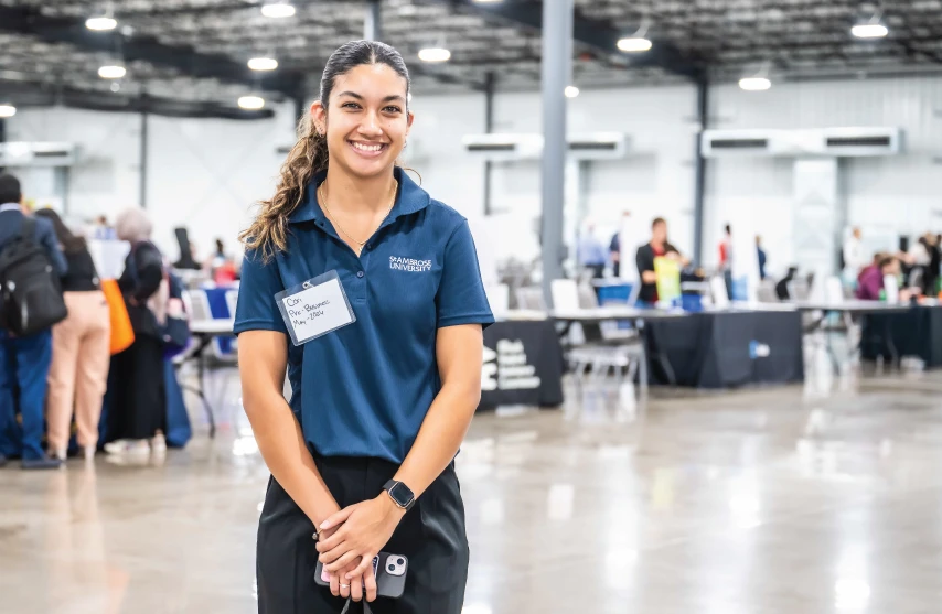 SAU student standing in center of expo center during career fair, smiling at camera.