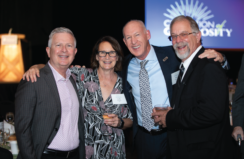 Four people smile together at event.