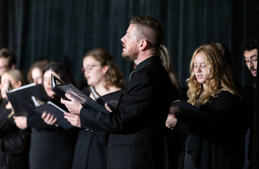 artists performing on a stage holding binders
