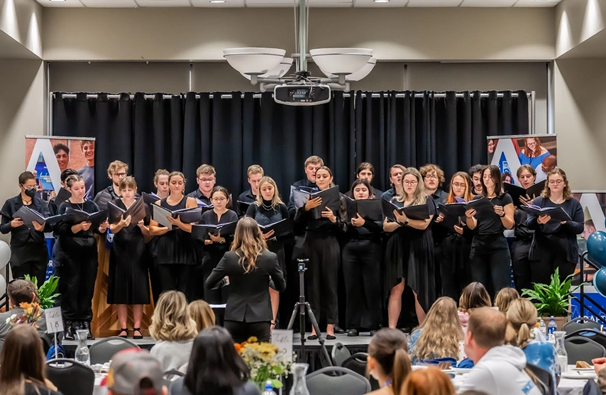 A student chorus performs for an audience.