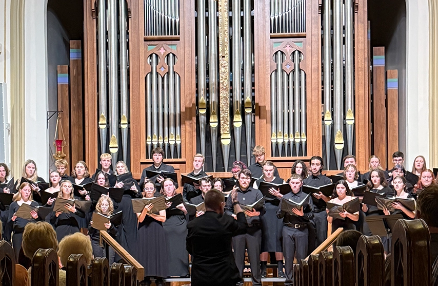 SAU's choir performs in front of an organ for a crowd.