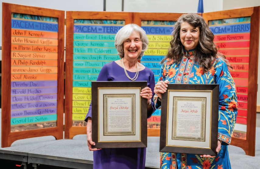 Two women holding up awards and smiling.