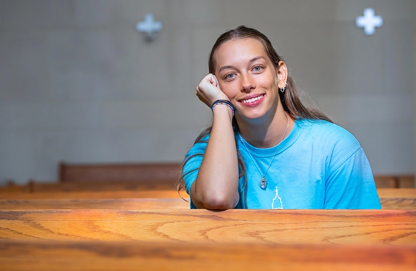 Anna Gute smiles into the camera while sitting in a pew.