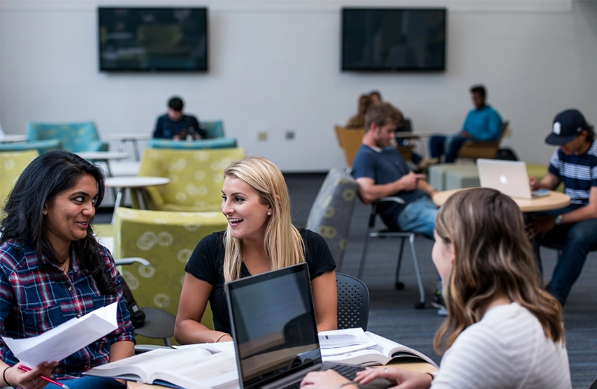 A group of students sit around a table with their textbooks open.