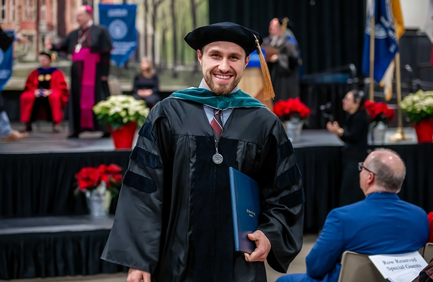 A newly hooded graduate returns to his seat.