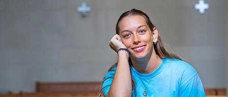 Anna Gute smiles into the camera while sitting in a pew.