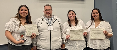 Felicity Emmerich, Associate Professor Justin Rice, Alina Maca, and Lluvia Garcia pose for a photo at the Minnesota Academy of Science 2026 Winchell Symposium Awards ceremony, with students holding award certificates.