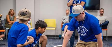 An instructor works with children during the coding summer camp.