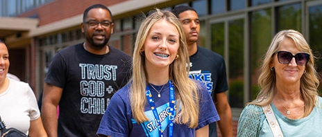 A small group of people tour St. Ambrose University, some smile into the camera.
