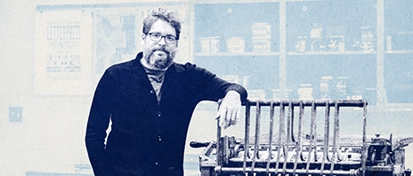 Associate professor and chair Joseph Lappie, MFA, poses next to printing equipment in his classroom.