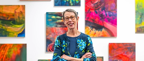 Kristin Quinn, MFA, stands in front of her “Luminous Flux Paintings from the Watershed” art collection on display at the Figge Art Museum,