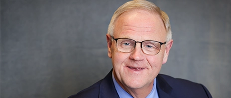 Todd Olson, PhD, smiles into the camera against a grey background.