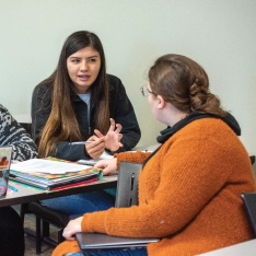 Two students engaged in a lively conversation while sitting at a table.