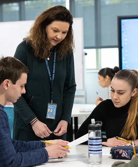 Female teacher leading a group of students at a table.