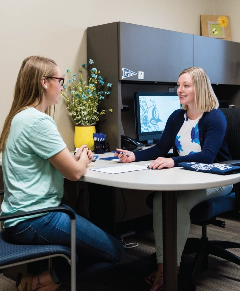 Admissions counselor at a desking helping a student.