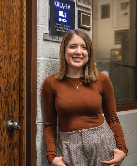 Student smiling outside radio studio.