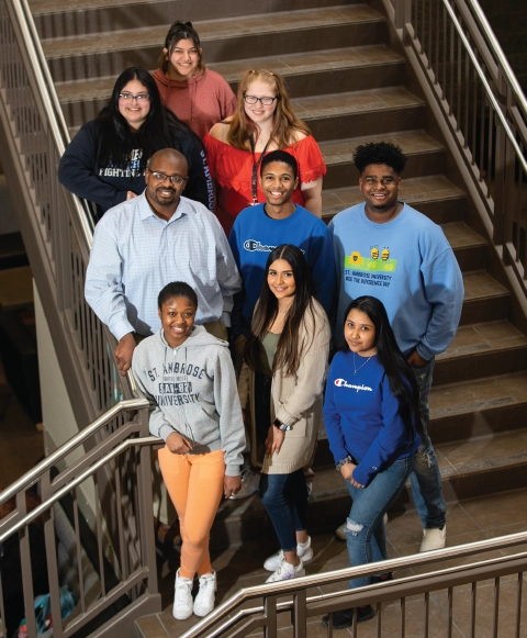 Student leaders in DEI initiatives standing on staircase together, smiling for photo.