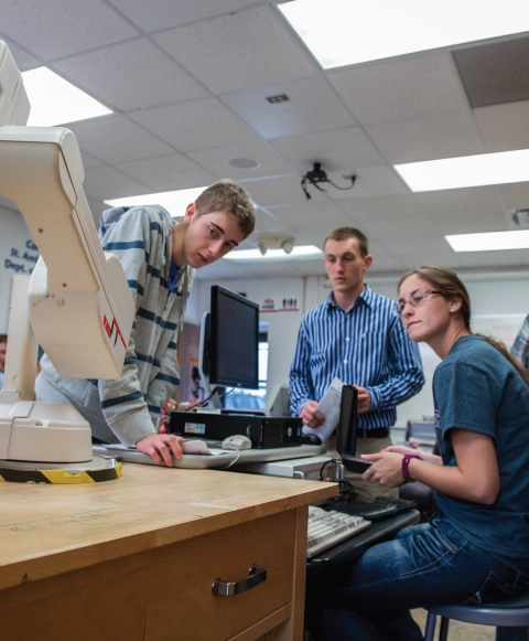 Group of engineering students collaborating on a project in a lab.