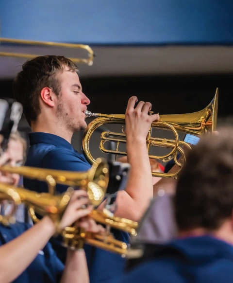 Member of pep band playing indoors.