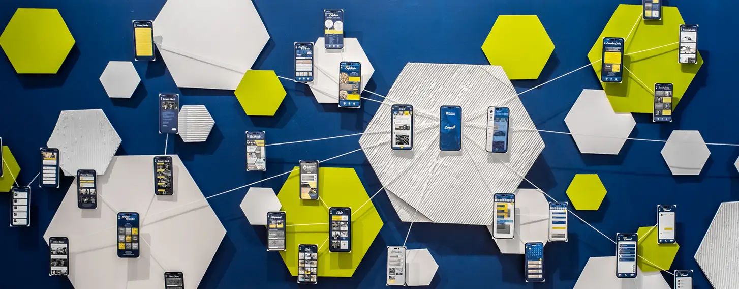 A graphic design exhibit on a blue wall featuring the UX experience for a mobile app.