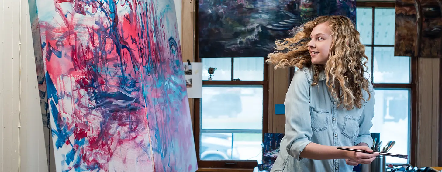 A female artist painting on a canvas in an art studio.