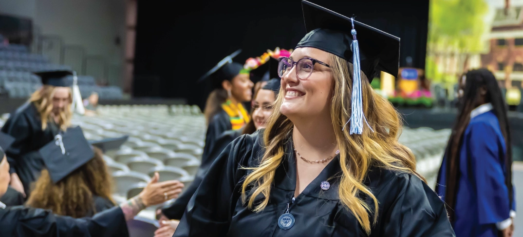 Bachelor student smiling during commencement ceremony.