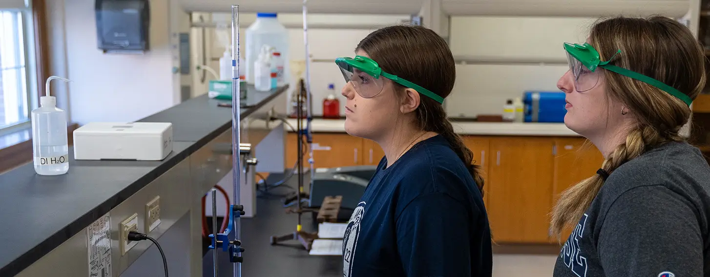 Two women in a chemistry lab conducting experiements and analyzing data.