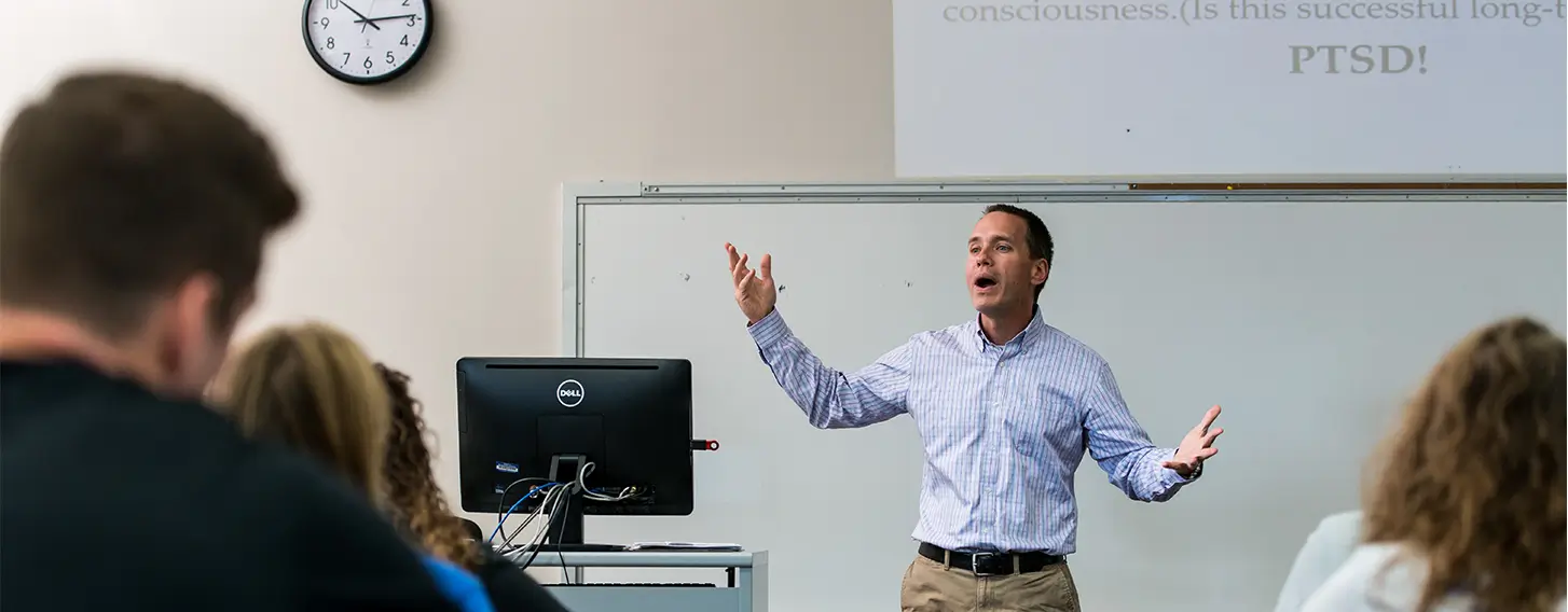 A man teaching in a classroom filled with attentive students.