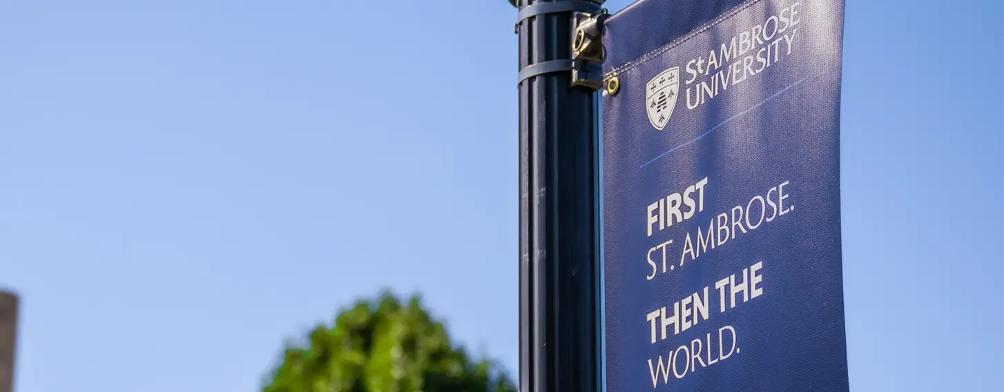 A St. Ambrose sign hanging from a post that reads 