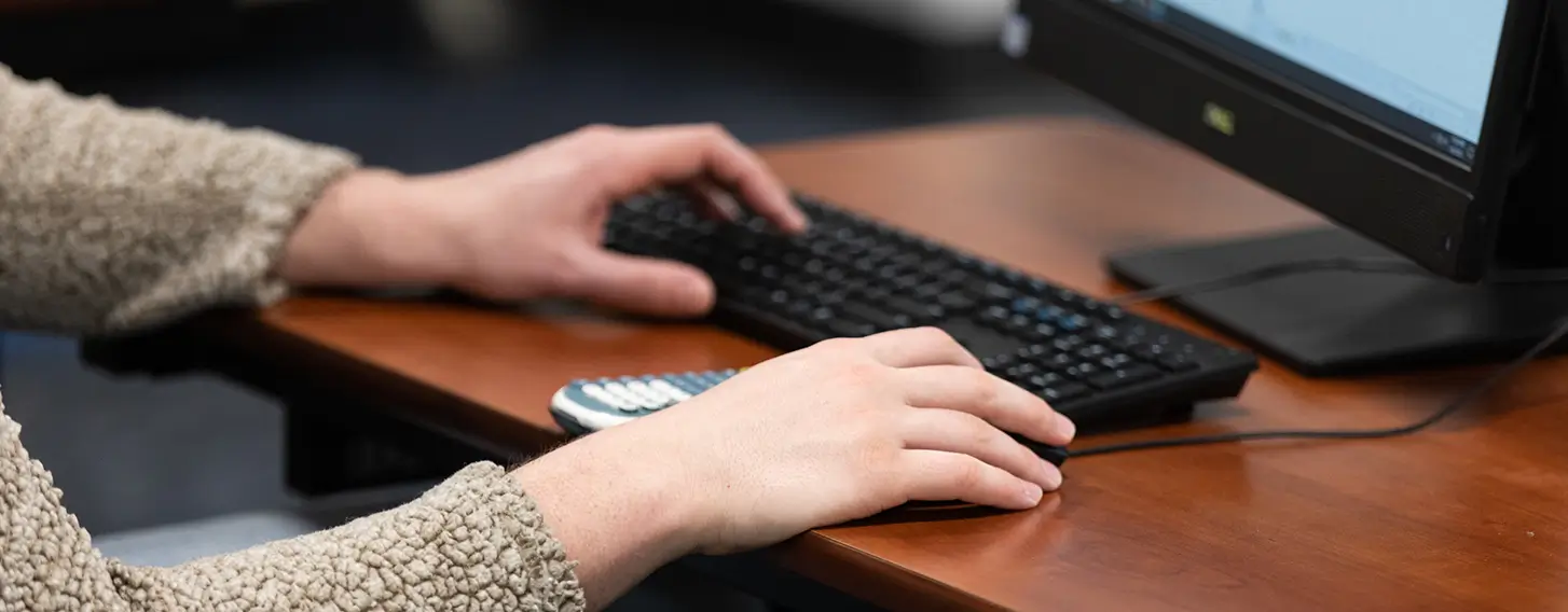 A student typing at a computer on a keyboard