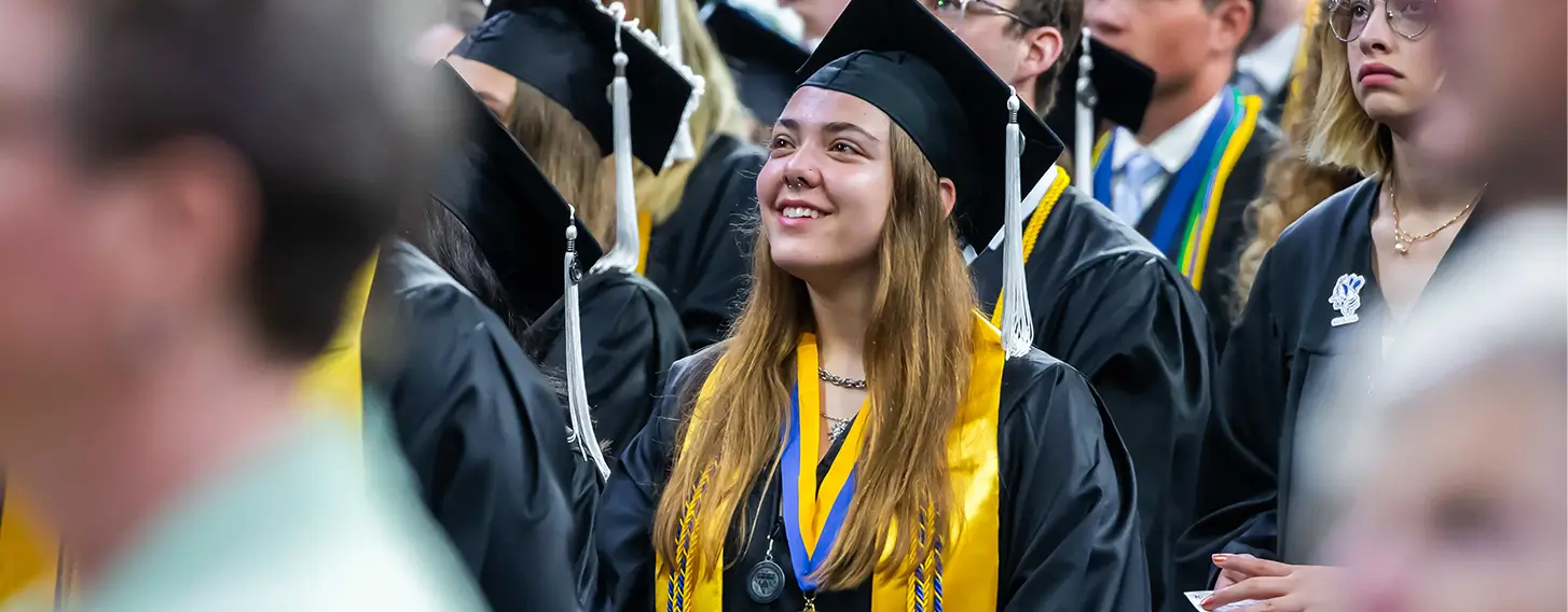 A smiling girl in a graduation gown during the commencement ceremony.