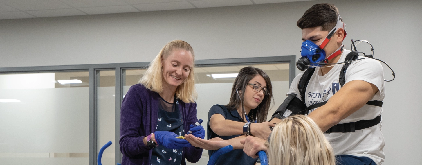 Group of exercise physiology students and teacher conducting assessment in kinesiology lab.