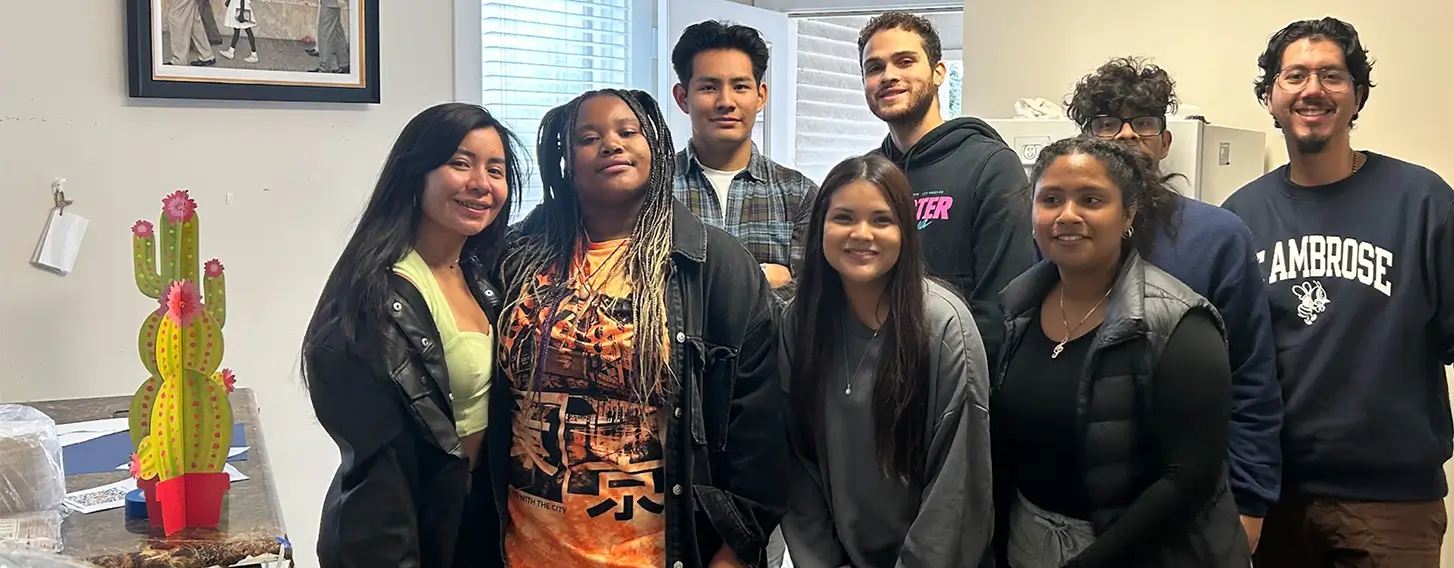 A group of students from latino unidos posing in front of the Greater Quad Cities Hispanic Chamber of Commerce.