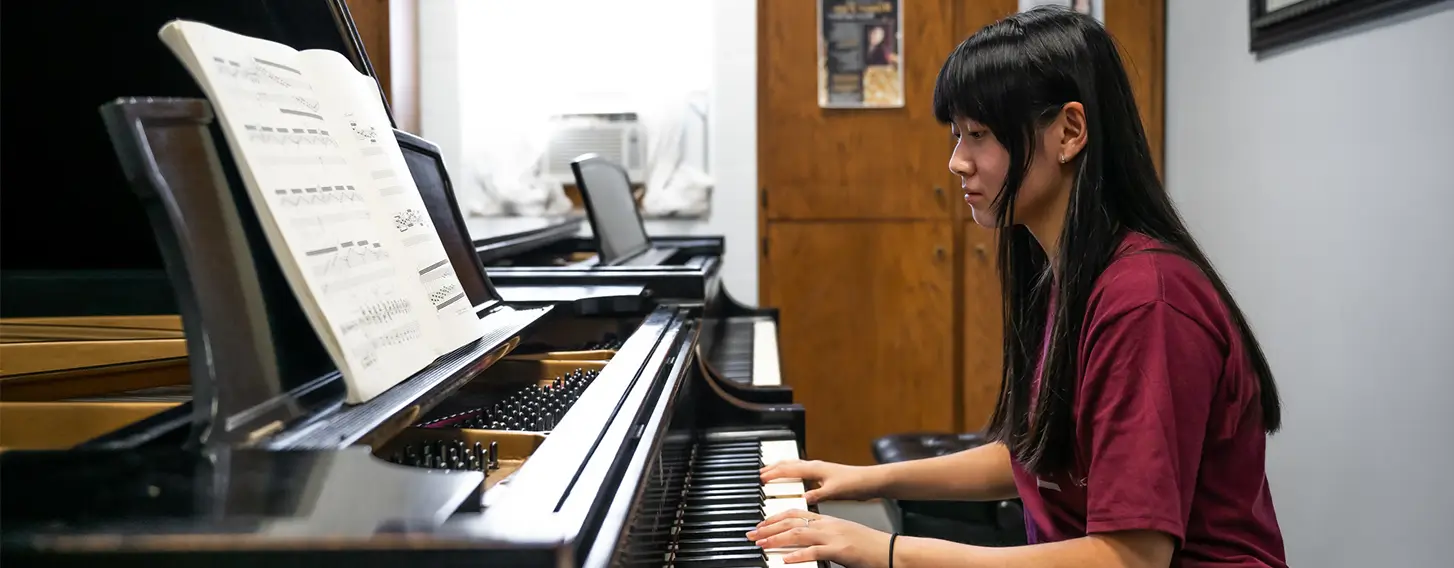 Woman sitting at the piano with her hands on the keys.