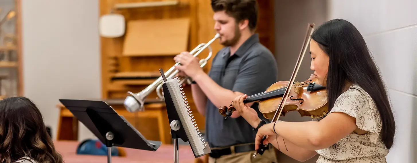 A man playing the trumpet and a woman playing the violin.