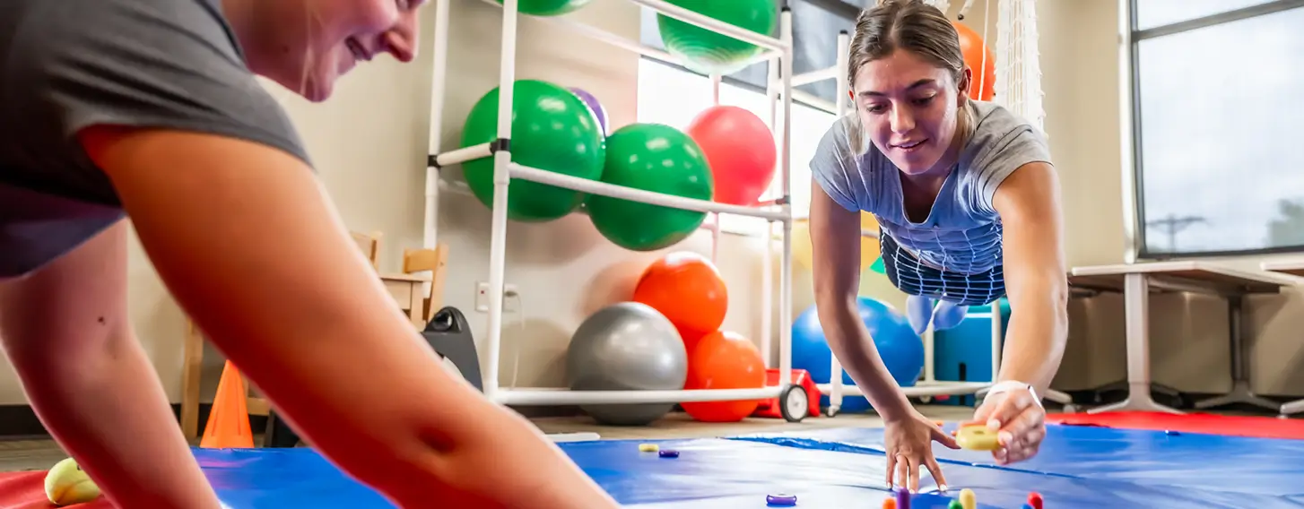 Two students participating in a sensory and motor skills assessment in an occupational therapy classroom.