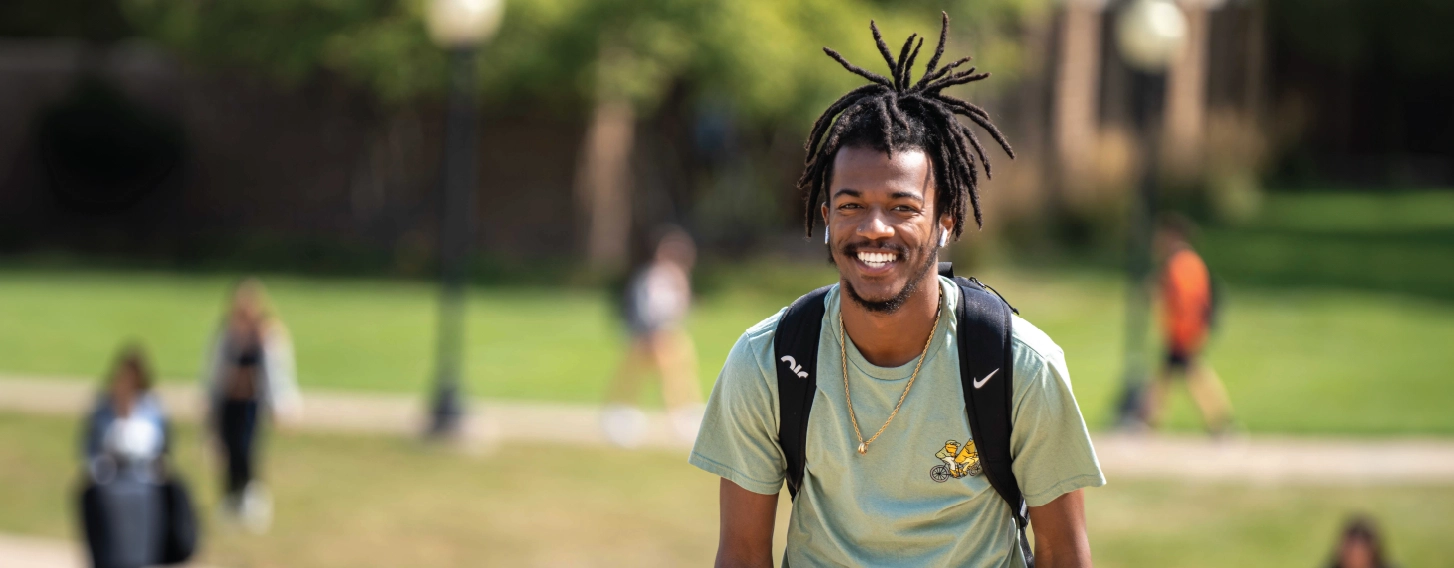 One student smiling outdoors while walking.