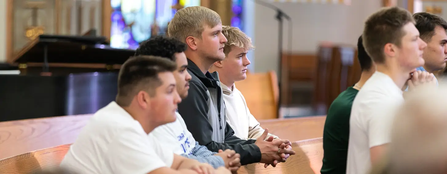 Students kneeling in prayer during mass